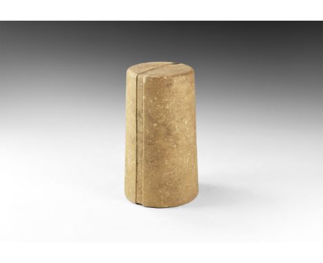 2nd millennium BC. A squat fossiliferous limestone columnar idol, slightly tapering with shallow slot to both flat faces and 