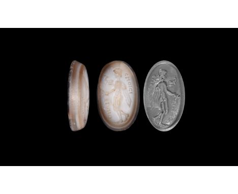 3rd-7th century AD. A plano-convex banded agate appliqué with intaglio motif of Hermes(?) advancing with fronds in one hand a