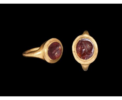 2nd-3rd century AD. A gold finger ring comprising a round-section hoop and drum-shaped bezel with inset garnet cloison, intag