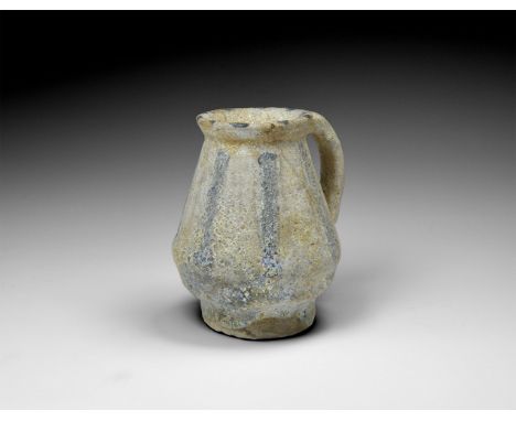 11th-12th century AD. A glass jug with slightly flared rim; sloping body with blue and white vertical stripes; collar to the 