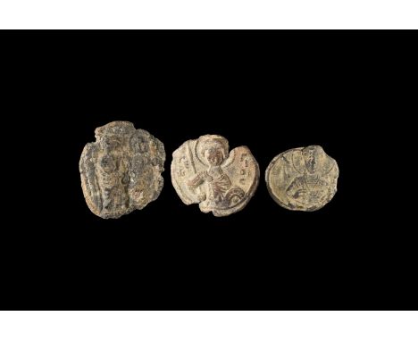 5th-8th century AD. A mixed group of three lead seals comprising: one with two facing robed figures holding a pole between; o