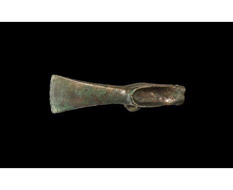 2nd millennium BC. An unfinished palstave axehead with flared blade, two lateral scooped flanges and small loop above; castin