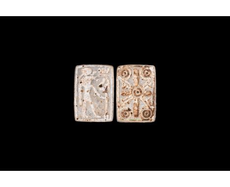 Saite Period, 624-525 BC. A white glazed composition amuletic plaque with profile figure of falcon-headed Khonsu holding a st