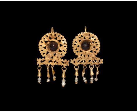 3rd century AD. A matched pair of gold earrings, each an openwork discoid plaque with central garnet sphere, scrolled plaque 