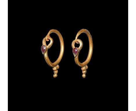 1st-2nd century AD. A matched pair of gold earrings, each a thick round-section hoop with hook-and-eye closure, granule clust