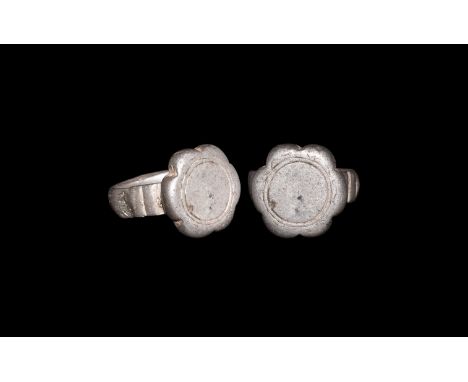 9th-11th century AD. A silver ring with flat section shank, ribbing to the shoulders and bezel in the form of a six petalled 