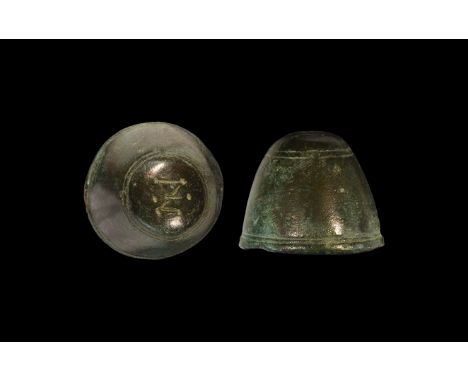 8th-10th century AD. A bronze weight, round in plan with conical body and domed cap, concave underside; incised circumferenti