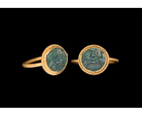 3rd-4th century AD. A gold finger ring with round-section hoop supporting a discoid plaque with beaded wire collar, inset gre