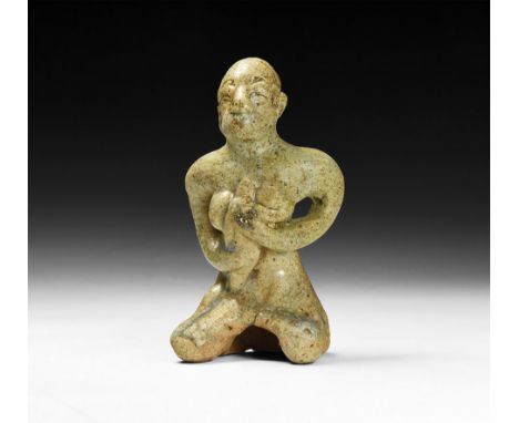 12th-16th century AD. A green-glazed ceramic figurine of a nude seated female suckling a baby in her arms; hollow to the unde