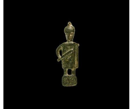 1st-3rd century AD. A bronze brooch in the form of a advancing gladiator, helmet covering face, short tunic to knees and righ