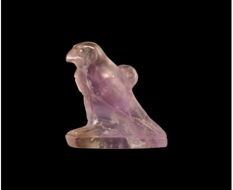 Late Period, 664-332 BC. A carved amethyst amulet of Horus in the form of a falcon standing on a rectangular plinth, wings fo