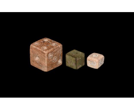 1st-4th century AD. A group of three dice, two bone, one bronze, each with engraved ring-and-dot motif to each face for numbe