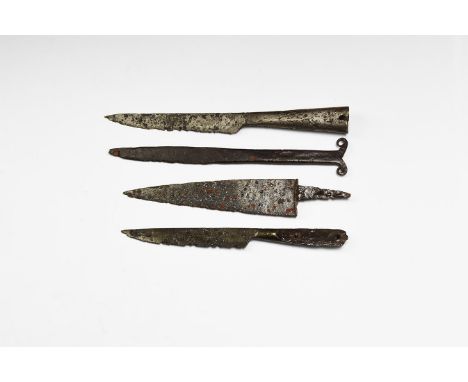 12th-15th century AD. A mixed group of iron single-edged knives comprising: one slender with curved edge, open socket to atta