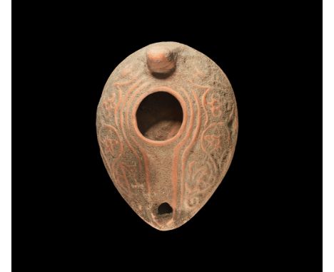 5th-8th century AD. A terracotta oil lamp, ovoid in plan with basal ring and convex sides, stub handle to the rear, running t