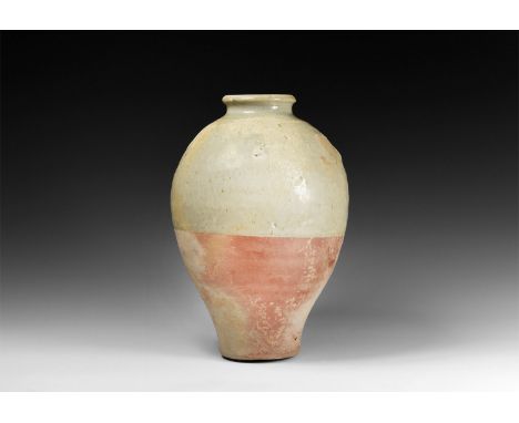 Tang Dynasty, 618-906 AD. A tall ceramic whiteware jar with flat base, high shoulder, waisted neck and rolled rim; part-glaze