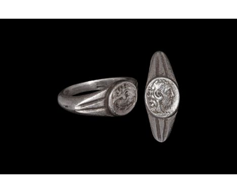 3rd century AD. A large silver finger ring comprising a D-section hoop with enlarged segmented shoulders, discoid plaque with