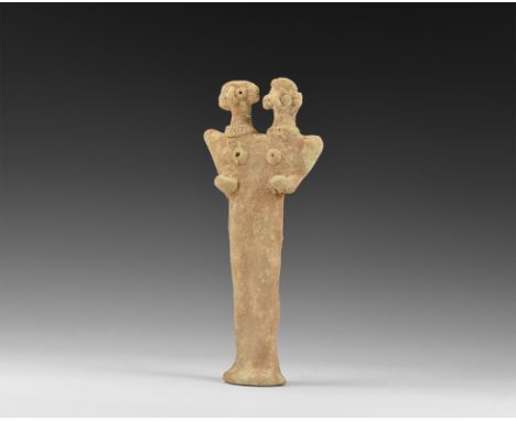 12th-7th century BC. A flat-backed ceramic figurine depicting a deity with two heads; the eyes and breasts formed with round 