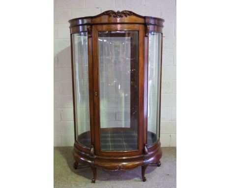 A large mahogany oval free standing shop display cabinet, circa 1900, with six bowed and bevelled glass panels, including doo