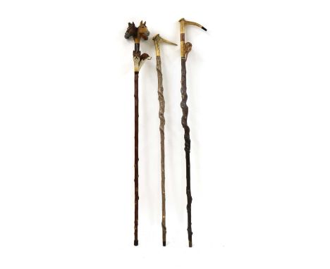 A group three carved walking sticks by Sam Wright of Norfolk,of recent manufacture, the first with four horses heads, fox, ho