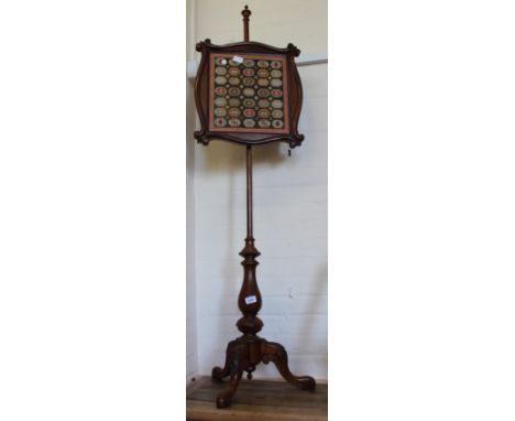 A Victorian pole screen with tapestry decorated shield and carved tripod base