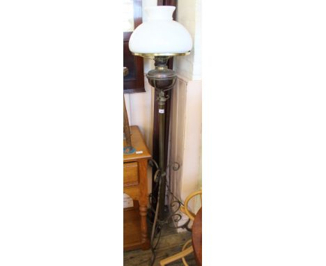 A brass oil lamp on stand with white shade