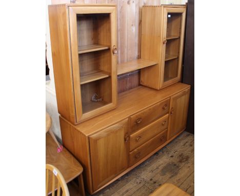 A 1970's light Ercol unit combining glazed cupboards and shelves with further cupboards and drawers below