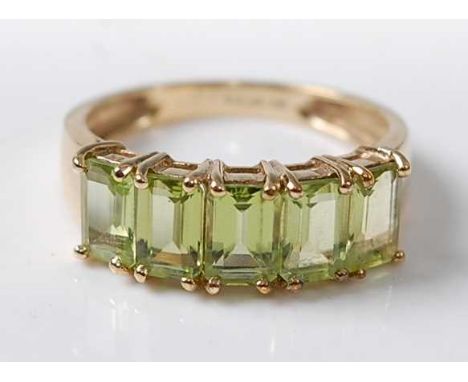 A 9ct yellow gold peridot dress ring, featuring five rectangular cut peridots in vertical claw settings, peridot dimensions e