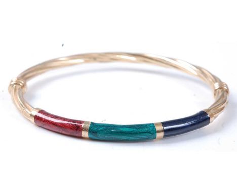 A yellow metal twist hollow hinged bangle, having red, green and blue enamel detail to the front and a figure-of-eight safety