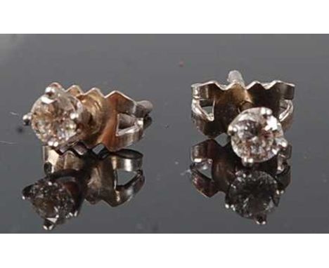 A pair of white metal diamond stud earrings, each featuring a round brilliant cut diamond in a four-claw setting, with post a