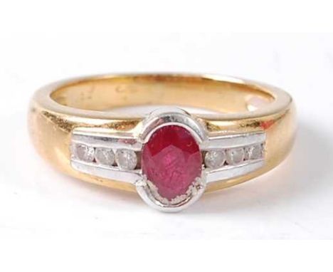 An 18ct yellow and white gold ruby and diamond ring featuring a centre oval faceted ruby in a semi bezel setting with three b