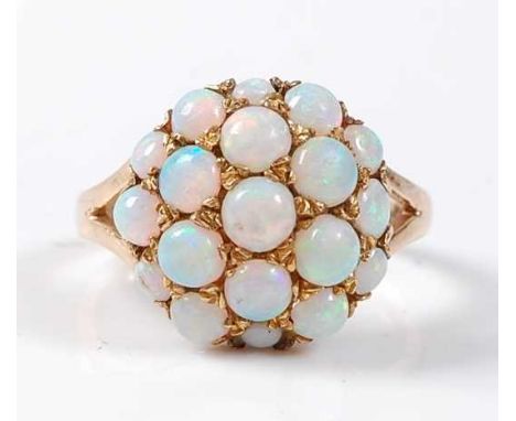 A 9ct yellow gold and opal bombe ring, featuring nineteen round cabochon cut opals in grain settings, with bifurcated shoulde