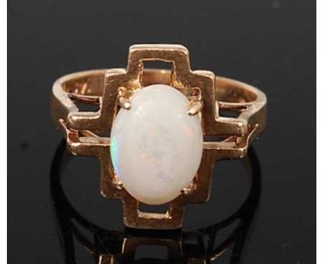 A yellow metal opal dress ring, featuring an oval opal cabochon set within an abstract openwork border, opal dimensions appro