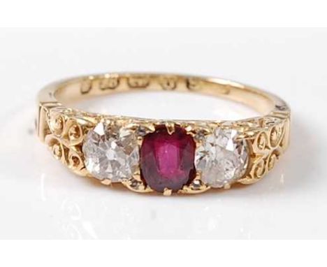 A late Victorian 18ct yellow gold, ruby and diamond three stone ring, featuring a centre oval faceted ruby with an Old Europe