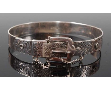 A sterling silver oval engraved bangle in the style of a belt, with safety chain, bangle diameter approx 63 x 52mm, bangle wi