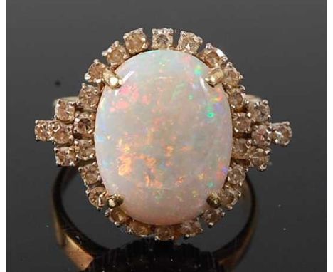 A yellow and white metal opal and diamond oval cluster ring comprising an oval opal cabochon within a border of 30 single cut