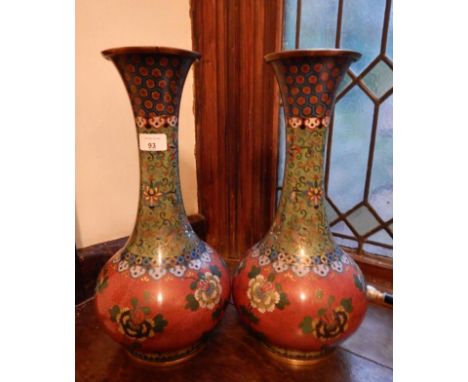 A pair of 20thC cloisonne bottle vases, with flared rims and tapered necks, decorated with Chrysanthemums on a coral ground a