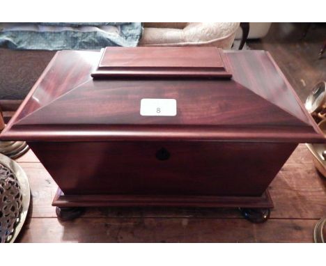A Victorian flamed mahogany sarcophagus three section tea caddy, with fitted interior, ebony escutcheon and turned feet.