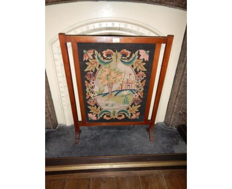A mahogany firescreen, with wool needlework panel.