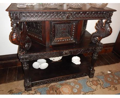 A Jacobean style oak credenza, with guilloche carved frieze, three panel centre compartment on shelf supported by stylised Gr