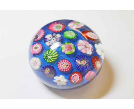 Clichy spaced millefiori paperweight, concentric cane arrangement with a central pink clichy rose on a mid blue carpet ground