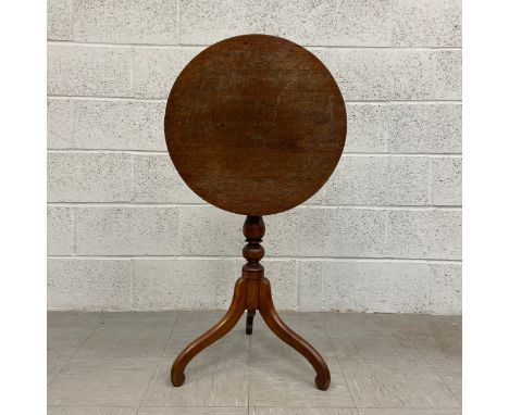 A 19th century oak occasional table having a circular top with a tilt action raised on a turned baluster form stem on splayed