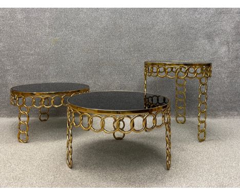 A set of three 20th century occasional tables by Hanbel each having a circular black glass top resting in a gilt metal oversi