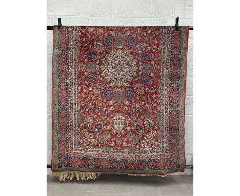A 19th century Persian style Kashan carpet having a central medallion surrounded by scrolling foliate designs with biscuit sp