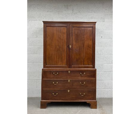 A Georgian mahogany press cupboard having a moulded cornice over two panelled cabinet doors revealing an interior with two pu
