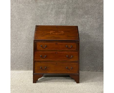 A Edwardian mahogany bureau having a marquetry inlaid fall front opening on to a fitted interior above three graduating satin