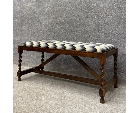 An early 20th century Utility Furniture Scheme oak Ottoman or footstool having a rectangular reupholstered drop in seat in a 