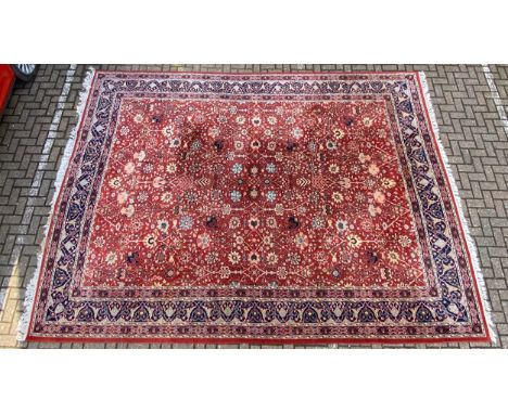A very large 20th century Persian style Sarouk carpet having a scrolling foliate field over a burgundy ground within multiple