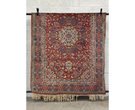 A 19th century Persian style Kashan carpet having a central medallion surrounded by scrolling foliate designs with biscuit sp