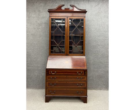 A Georgian style mahogany bureau bookcase having a shaped pediment above two glazed doors, the lower section having an inlaid