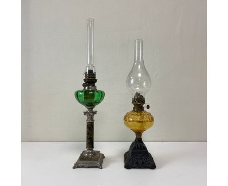 Two C.1900 Art Nouveau style brass and coloured glass oil lamps to include one with a tall clear chimney over a ovoid green g